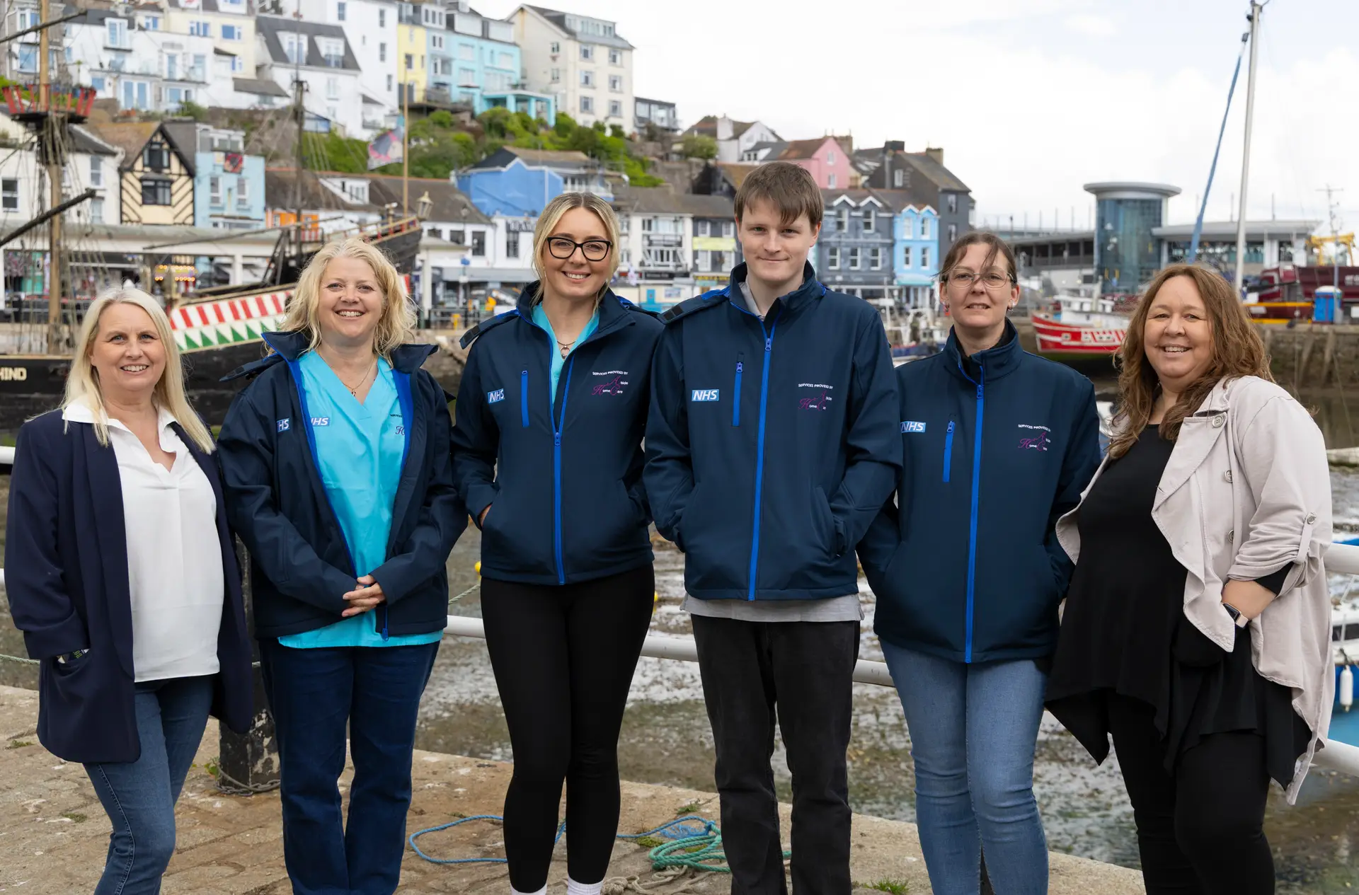 Abide Home Care team members standing together along the coastal Brixham harbor.
