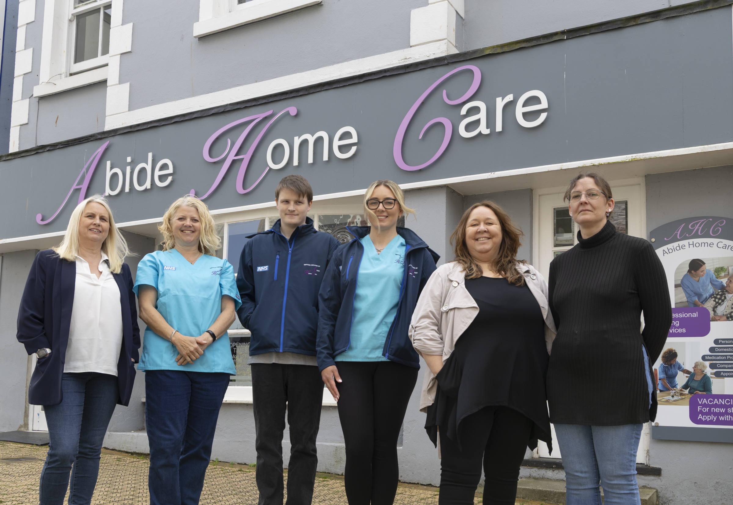 The Abide Home Care team standing together in front of their office building in Brixham.